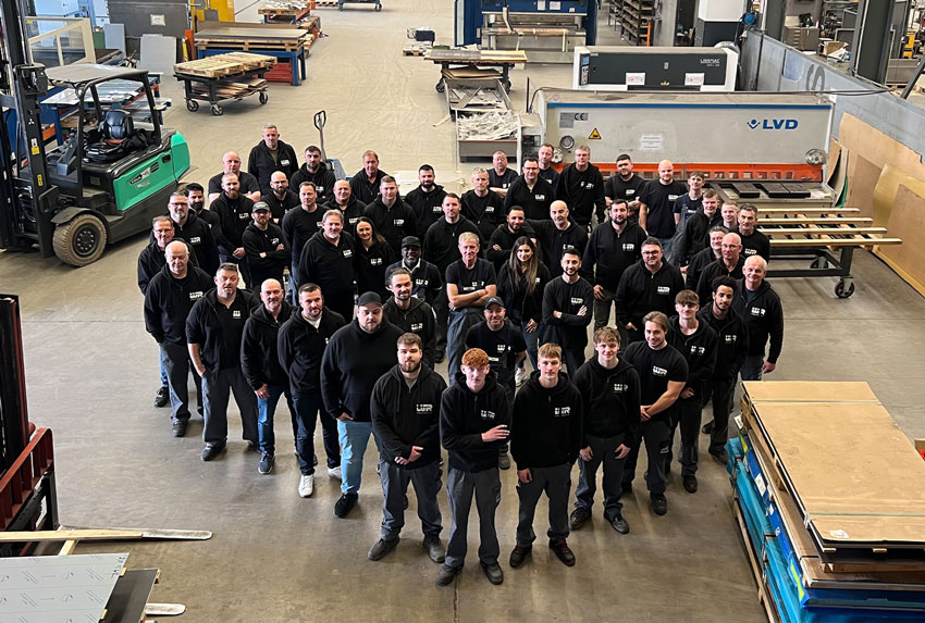 W. Rausch Gruppenfoto von allen Mitarbeitern in der schwarzen Firmenkleidung in der Produktion