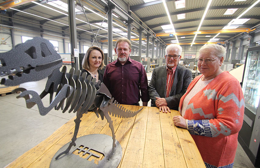 Familie Rausch auf einem Gruppenfoto mit dem Firmensymbol des Dinos in der Produktionshalle